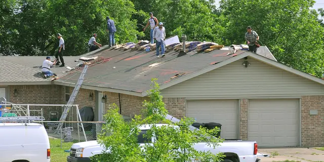 A team of roofers working together on top of a one-story house